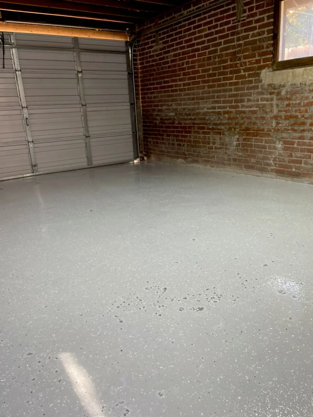 Flake floor coating in a brick-walled Denver garage with the door open